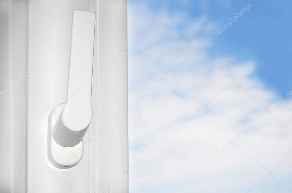 plastic window with a handle and a view of the sky with clouds.