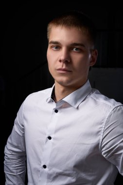 Genç bir adamın yakın plan portresi, mutlu, neşeli, yakışıklı iş adamı modern ofiste beyaz gömlekle duruyor.