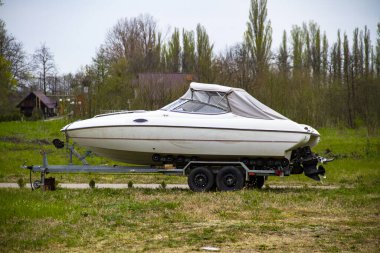 Motorlu beyaz tekne ormanın arka planında bir karavanda duruyor ve nakliyeye hazır.
