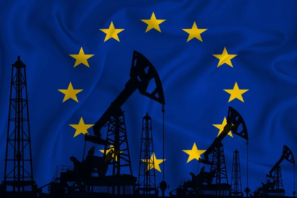 Silhouette of drilling rigs and oil derricks on the background of the flag of European Union. Oil and gas industry. The concept of oil fields and oil companies.