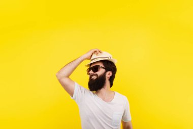 Sakallı, gülümseyen adam, yaz havasında, sarı arka planda.