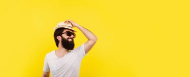 Sarı arka planda yaz havasında sakallı, gülümseyen bir adam, panoramik bir maket.