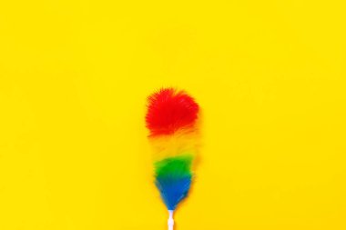 Sarı arka planda renkli tüy tozu. Temizlik kavramı.