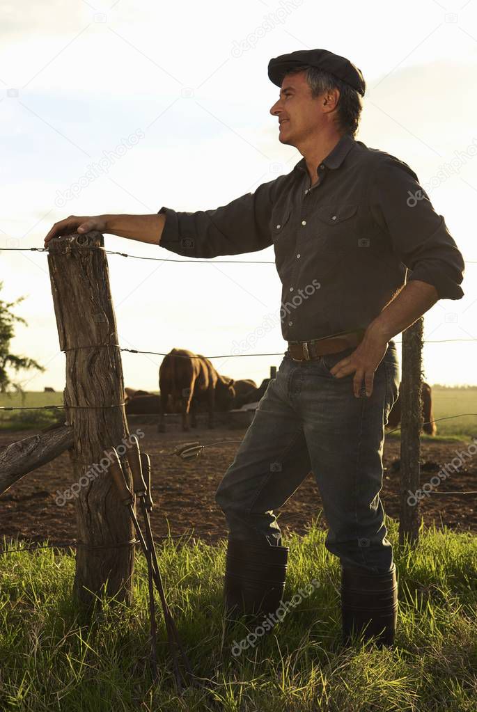 senior man standing near wooden fence 