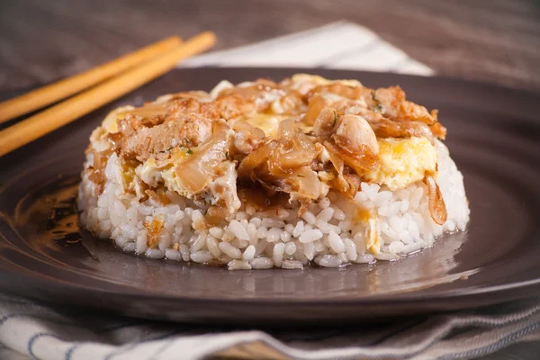 Arroz con salsa de pollo en un plato oscuro y una toalla de lino en el —  Fotos de Stock