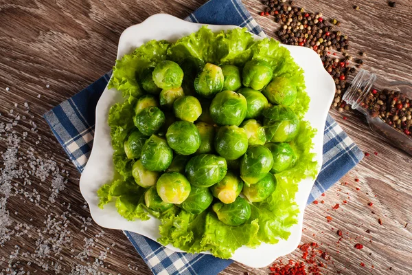 Brussels sprouts on a white plate on a background of a linen tow — Stock Photo, Image