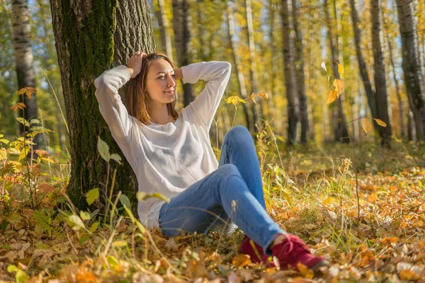 Молодая девушка сидит под деревом — стоковое фото