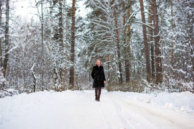 Kız kış orman içinde karlı bir yol yürür.