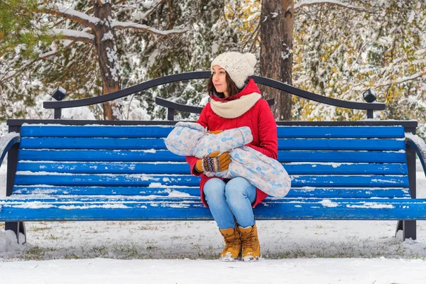 Мать с ребенком в руках сидит на скамейке в парке — стоковое фото