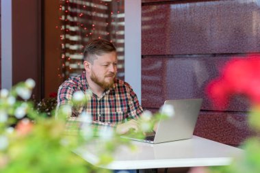 Kafede oturan ve bir dizüstü bilgisayar arayan adam