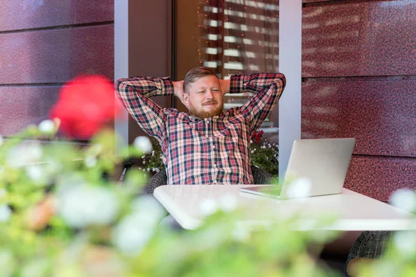 El hombre sentado en el café en la mesa y mirando un portátil — Foto de Stock