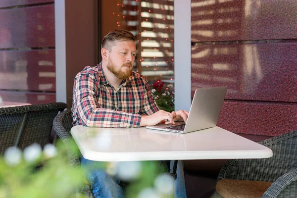 El hombre sentado en el café en la mesa y mirando un portátil — Foto de Stock