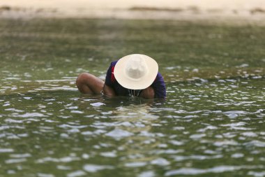 Denizde oturan ve ahtapot yakalamak bir adam