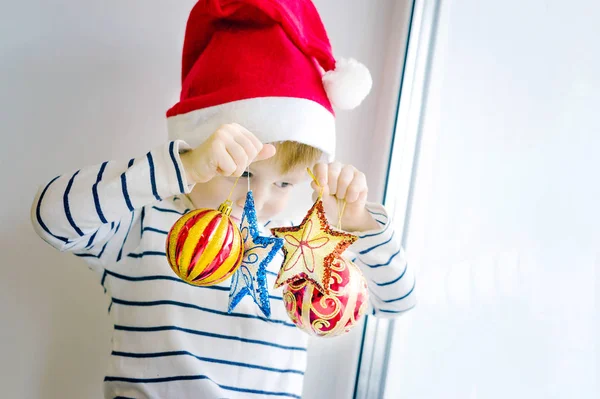 Мальчик в красной шляпе с рождественскими игрушками — стоковое фото