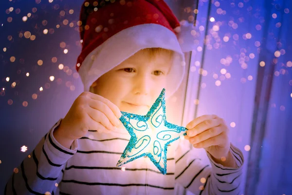 Мальчик в красной шляпе с игрушкой для елки - звезда — стоковое фото