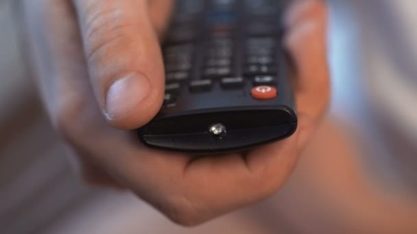 Mans hand with remote control includes TV — Stock Video