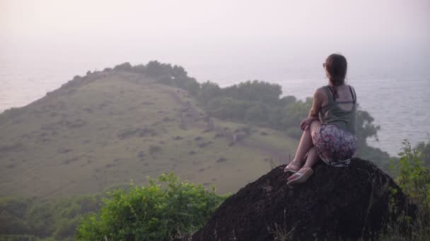 Girl sitting in the mountains at sunset. — Stock Video