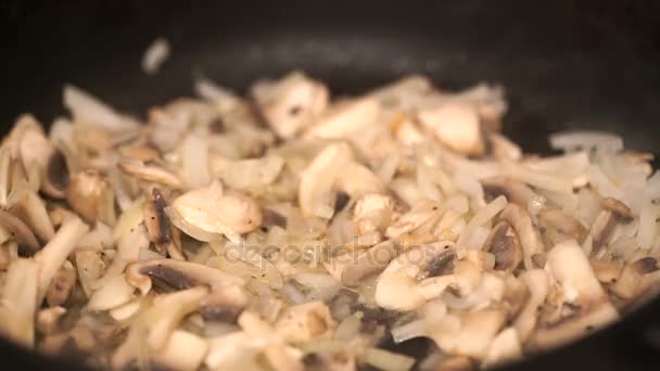 Primer plano de deliciosos champiñones de botón rebanados fritos con cebolla y aceite en la sartén — Vídeo de stock