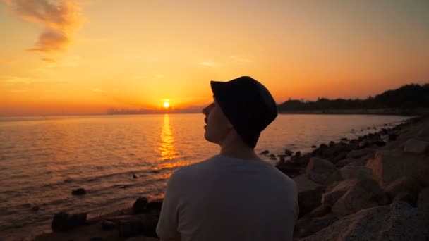 Человек, стоящий на пляже и наблюдающий за закатом — стоковое видео
