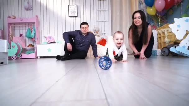 Gelukkige ouders liggen met hun schattige baby zoon op bed thuis in slaapkamer — Stockvideo