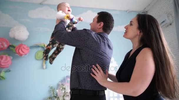 Concepto de familia, paternidad y personas: madre y padre felices jugando con el bebé en casa — Vídeo de stock