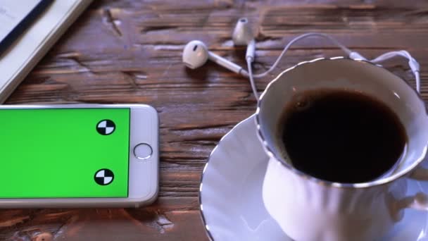 Tasse à café à côté de l'appareil mobile à la fois sur une table en bois. Plan studio . — Video