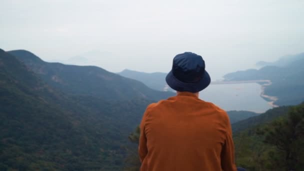 Retrato de un hombre calvo sentado en la cima de la montaña mirando el horizonte — Vídeo de stock