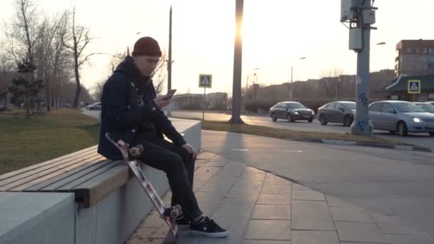 Человек сидит на скейтборде и едет прочь — стоковое видео