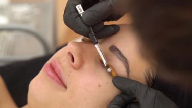 Güzellik Salonundaki Güzel Bir Kız Ağıt Kirpikleri Yapıyor. Güzellik uzmanı, göz kirpiklerinin parçalanmasını gerçekleştiriyor. Kapat.