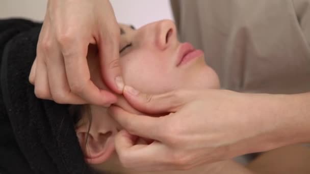 Спа жінка масаж обличчя. Обличчя Масаж в салоні краси. Жінка насолоджується розслабляючим масажем обличчя в косметологічному спа-центрі . — стокове відео