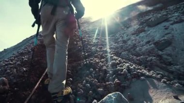 İlkbaharda ya da yazın soğuk bir günde dağlardaki kayalıklarda yürüyüş yapan yürüyüşçü adam. Gün batımında ya da gün doğumunda arka planda güneş ışığı. Spor..