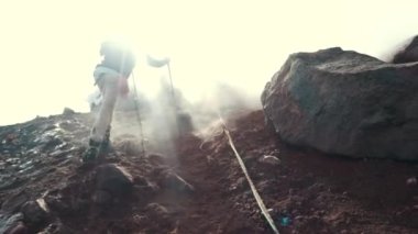 İlkbaharda ya da yazın soğuk bir günde dağlardaki kayalıklarda yürüyüş yapan yürüyüşçü adam. Gün batımında ya da gün doğumunda.