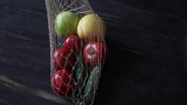 Reusable grocery bags with fruits and vegetables, reusable water bottle on the kitchen on black wooden table. Zero waste home — ストック動画