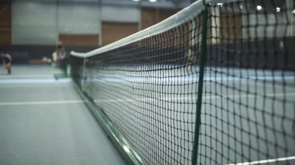 Primer plano del equipo de tenis en la cancha. Deporte, concepto recreativo. Bolas de tenis amarillas golpean la red en una cancha verde arcilla azul junto a la línea blanca con espacio para copiar y enfoque suave — Vídeos de Stock