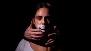 Aile içi şiddet ve sosyal sorunlar kavramı. Depresyondaki umutsuz kadın kameraya bakar ve yüzüne siyah arka planda bir gülücük koyar.