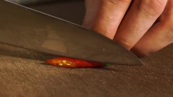 Los chiles rojos frescos se cortan con un cuchillo afilado en una tabla de madera. 4K cámara lenta — Vídeos de Stock