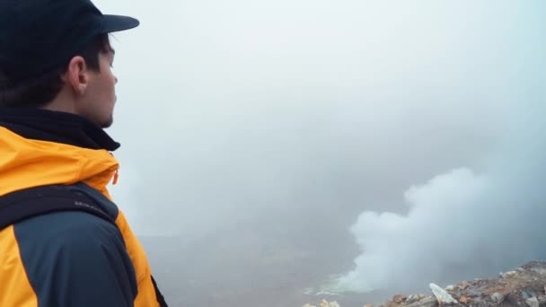 Мандрівник кладе на вершину сірчаного вулкана Хікерс рюкзаки, розслабившись на вершині пагорба і насолоджуючись краєвидом. Камчатка Росія — стокове відео
