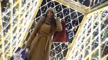 Noel alışverişi çantası, Noel arkaplan ışığı. Kadın, alışveriş torbalarıyla Avrupa Noel pazarının tadını çıkarıyor. Kış şehri caddesinde alışveriş yapan kız, Noel hediyeleri, mutlu yıllar.