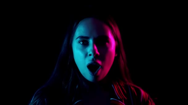 Verrast vrouw gezicht in neon licht. Sluiten van verrast meisje gezicht. Portret van mode model wow expressie. close-up van geschokte vrouw op zoek camera. — Stockvideo