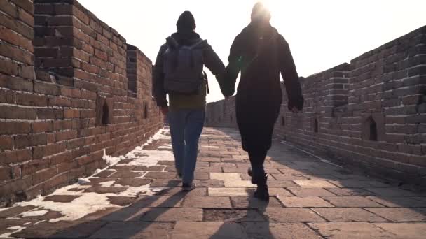 Pareja explorar Gran Muralla de China juntos, cámara baja en pavimento de piedra de amplio pasaje. Los turistas bajan tomados de la mano, disfrutan del sitio vacío de Mutianyu en invierno — Vídeo de stock