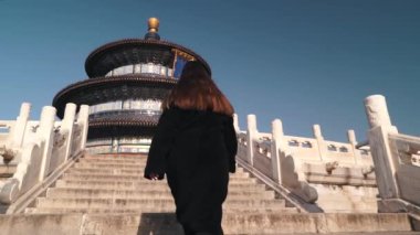 Kız turist kışın güneşli bir günde Pekin 'deki cennet tapınağına merdivenlerden çıkıyor. Seyahat kavramı.