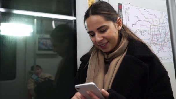 Retrato de chica sonriente en tren usando teléfono inteligente charlando con amigos mujer mano internet tecnología teléfono móvil ciudad teléfono móvil — Vídeos de Stock