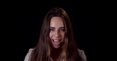 Zaferi kutlayan ve zaferin tadını çıkaran genç bir kadın stüdyoda konfetiye taşınarak iyi haberler kazandı. Siyah arka planda gülümseyen mutlu beyaz kız portresi,