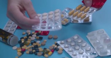 Elinde haplar, haplar, vitaminler, uyuşturucular, mavi arka planda izole edilmiş kapsüller olan bir erkek eli. Coronavirus tedavisi konsepti. Sağlık hizmeti konsepti. İlaç endüstrisi..