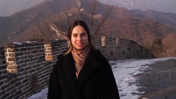 Beautiful tourist girl walks along the great wall of China at sunset in winter. Travel concept. — стокове відео