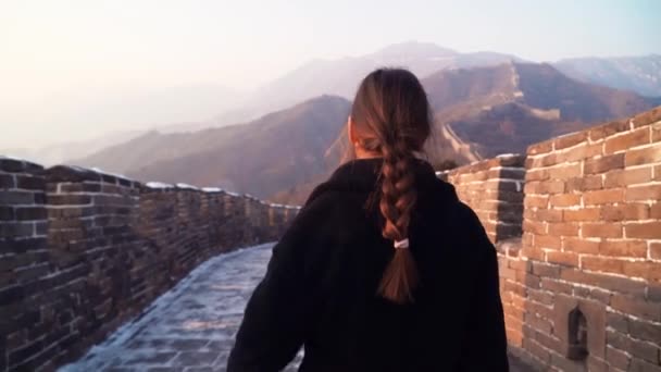 Une femme heureuse marche à la Grande Muraille de Chine, descend de la tour de guet de la section Badaling au coucher du soleil en hiver. Concept de voyage. Suivre le tir — Video