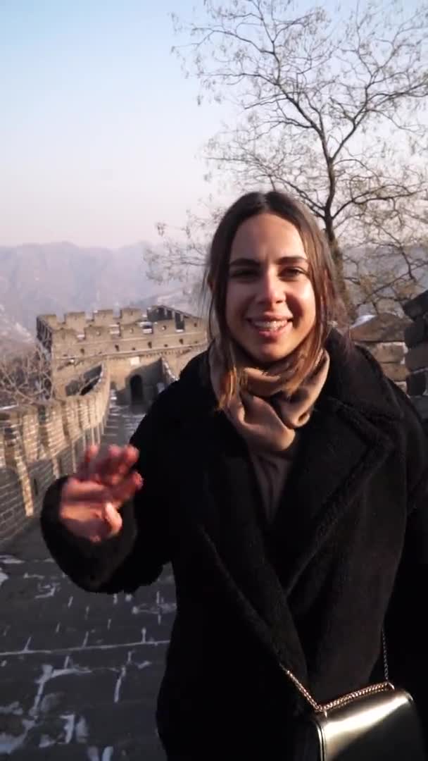 Bella donna che viaggia in Asia, si erge sulla Grande Muraglia Cinese scattando selfie o videochiamate durante la sua vacanza. Video verticale 9: 16 — Video Stock