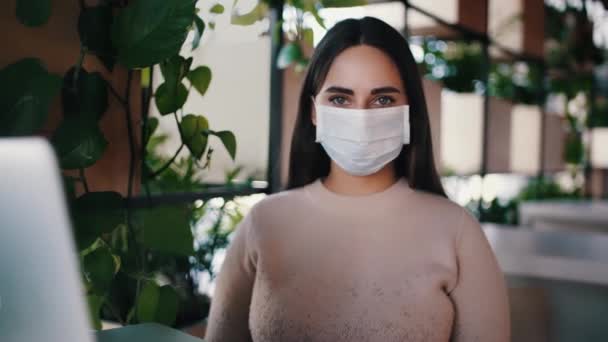 Retrato de uma mulher em uma máscara médica no local de trabalho durante um surto de coronavírus. Novel coronavirus 2019-nCoV concept . — Vídeo de Stock