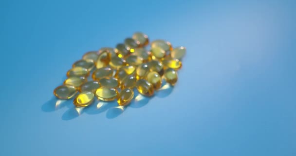 Omega 3 gouden visolie capsules, rotatie op blauwe achtergrond. Gezondheidszorgconcept. Farmaceutische industrie. — Stockvideo