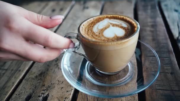 Close-up van de vrouw hand het plaatsen van hete koffie kopje op schotel over houten tafel in de straat cafe — Stockvideo